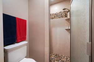 Bathroom featuring a tile shower and toilet