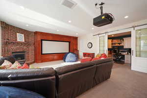 Carpeted cinema with a brick fireplace and a barn door