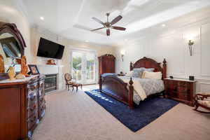 Primary Bedroom with access to exterior, light colored carpet, a raised ceiling, crown molding, and ceiling fan