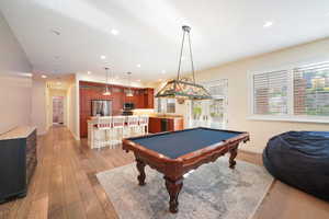 Recreation room featuring indoor wet bar, light wood-type flooring, and billiards