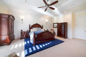 Primary Bedroom with ceiling fan, light colored carpet, and ornamental molding