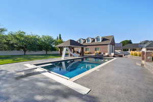 View of pool featuring a diving board, a yard, a water slide, and a patio area