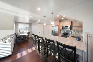 ADU - Kitchen featuring decorative light fixtures, sink, stainless steel appliances, and a breakfast bar