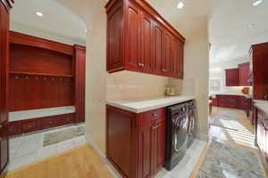 Clothes washing area featuring cabinets, light hardwood / wood-style floors, ornamental molding, and washing machine and clothes dryer