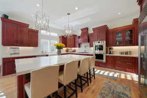 Kitchen featuring light wood-type flooring, a kitchen bar, custom range hood, a kitchen island, and an inviting chandelier