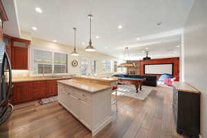 Kitchen featuring a breakfast bar, pool table, light stone counters, hardwood / wood-style flooring, and decorative light fixtures