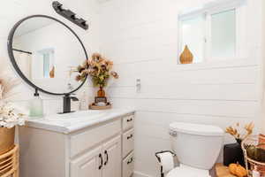 Bathroom featuring wood walls, vanity, and toilet