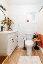 Bathroom featuring vanity, wood-type flooring, wooden walls, toilet, and a shower with shower curtain