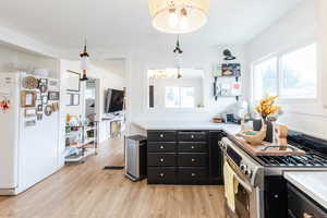 Kitchen featuring stainless steel stove, pendant lighting, white fridge, and a healthy amount of sunlight