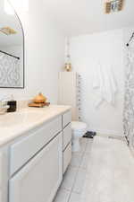 Bathroom featuring vanity, tile patterned flooring, and toilet