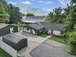 Back of house with an outbuilding, a mountain view, a lawn, and a garage