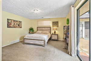 Carpeted bedroom featuring a textured ceiling and access to exterior