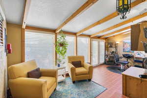 Living room with a textured ceiling, tile patterned floors, and beam ceiling