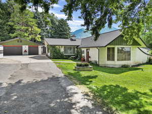 Single story home featuring a garage, a front lawn, and an outbuilding