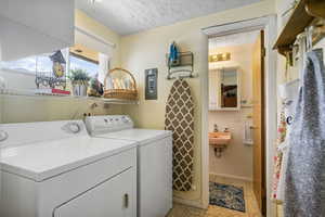 Washroom with sink, a textured ceiling, and separate washer and dryer