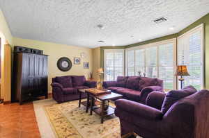 Tiled living room featuring a textured ceiling and a healthy amount of sunlight