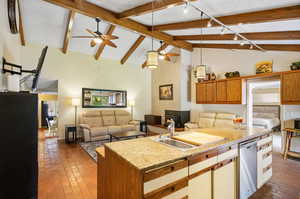 Kitchen featuring dishwasher, decorative light fixtures, sink, ceiling fan, and a kitchen island