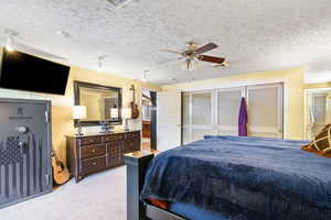 Carpeted bedroom featuring a textured ceiling and ceiling fan