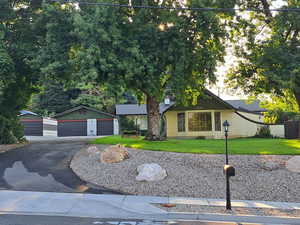 Ranch-style home featuring a garage, a front lawn, and an outbuilding