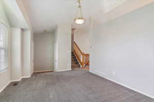 Carpeted empty room featuring a wealth of natural light and vaulted ceiling