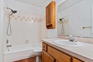 Full bathroom with hardwood / wood-style floors, tiled shower / bath, toilet, and vanity