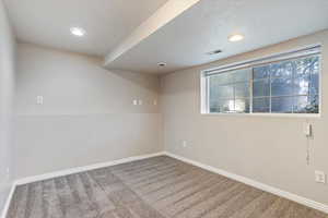 Carpeted spare room featuring a textured ceiling and a wealth of natural light