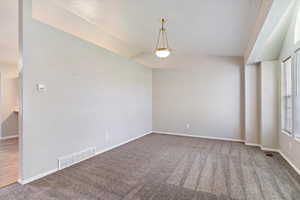 Unfurnished room with lofted ceiling, plenty of natural light, and carpet flooring