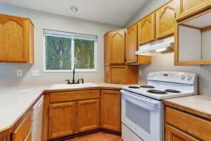 Kitchen featuring light wood-type flooring, white appliances, lofted ceiling, and sink