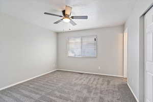 Interior space with a textured ceiling, ceiling fan, and carpet floors