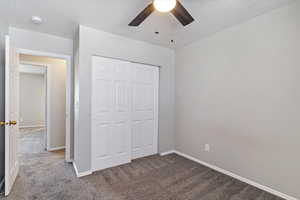 Unfurnished bedroom with a closet, ceiling fan, a textured ceiling, and carpet floors