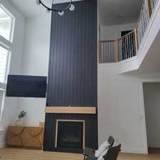 Living room with a towering ceiling, wood-type flooring, and a fireplace