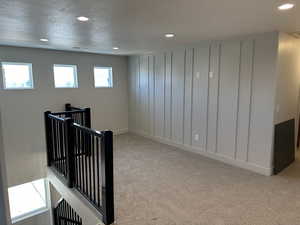 Corridor featuring light colored carpet and a textured ceiling