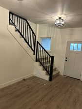 Foyer entrance with an inviting chandelier, a textured ceiling, and dark wood-type flooring