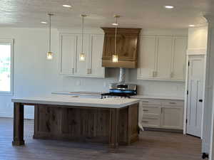 Kitchen featuring white cabinetry, dark hardwood / wood-style flooring, pendant lighting, and stainless steel gas range