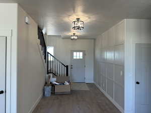 Foyer with an inviting chandelier, hardwood / wood-style flooring, and a textured ceiling