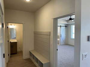 Mudroom featuring light hardwood / wood-style flooring, ceiling fan, and a barn door