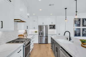 Kitchen featuring appliances with stainless steel finishes, sink, and white cabinets