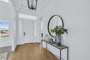 Foyer with a high ceiling, light hardwood / wood-style floors, and a chandelier