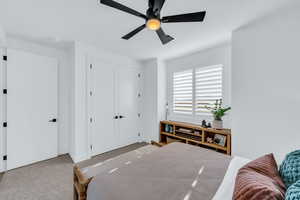 Carpeted bedroom with a closet and ceiling fan