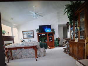 Living room with ceiling fan, light colored carpet, and a textured ceiling