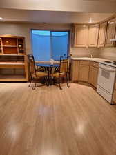 Kitchen featuring light brown cabinets, light hardwood / wood-style flooring, white range with electric stovetop, and sink