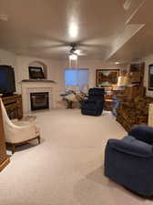 Living room with ceiling fan, a premium fireplace, and carpet