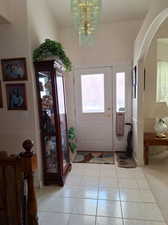 Entryway with light tile patterned floors and a chandelier