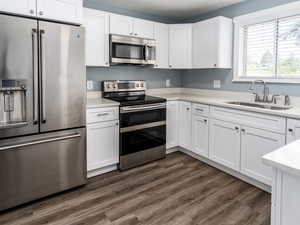 Kitchen featuring stainless steel appliances, white cabinets, dark hardwood / wood-style floors, and sink