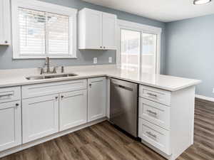 Kitchen with white cabinets, kitchen peninsula, sink, stainless steel dishwasher, and dark hardwood / wood-style flooring