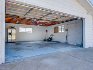 Garage featuring a garage door opener and stainless steel fridge