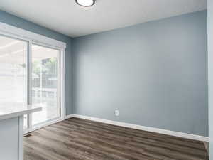 Unfurnished dining area with a textured ceiling and dark wood-type flooring