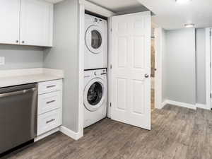 Laundry room featuring dark wood-type flooring and stacked washer and dryer