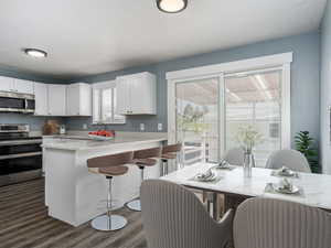 Kitchen with a breakfast bar, white cabinets, stainless steel appliances, and a wealth of natural light