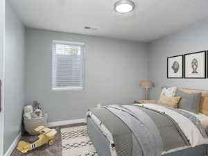 Bedroom with a textured ceiling and light carpet